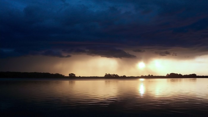 Sunset over a lake with dark clouds and reflections
