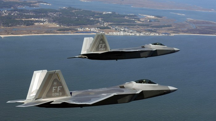 Two Lockheed Martin F-22 Raptors flying over water
