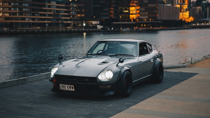 Grey Datsun 240Z with fender flares by the water
