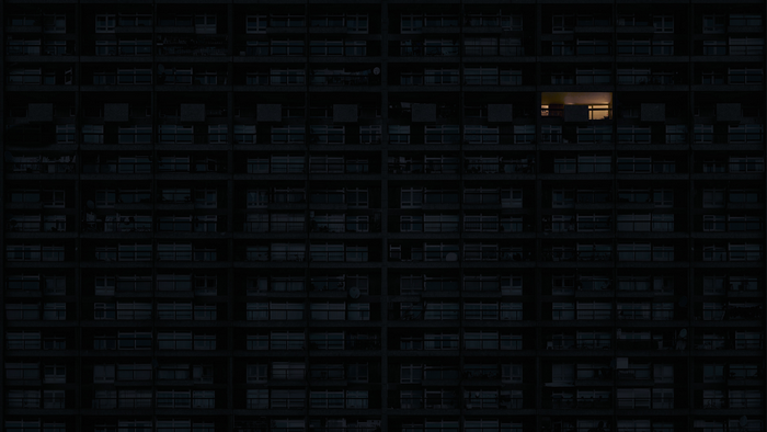 Apartment building at night with one lit window