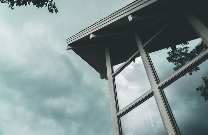Low-angle view of a modern building with large windows under an overcast sky