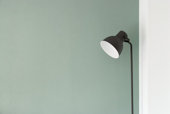 Minimalist floor lamp against a textured wall