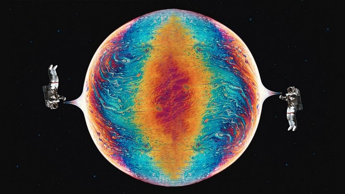 Astronauts interacting with a colorful bubble in space
