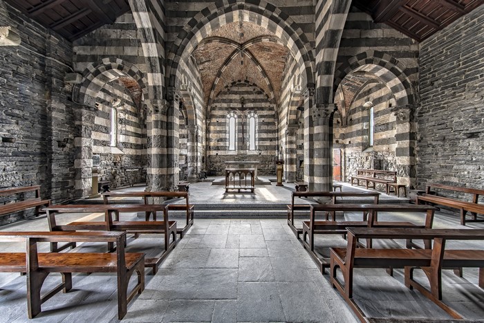 Interior of a striped stone church with wooden pews