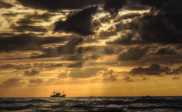 Fishing boat on the sea under dramatic clouds