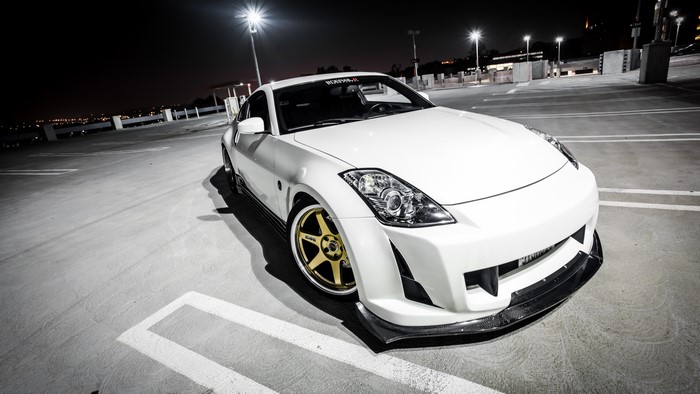 White Nissan 350Z with gold wheels in parking lot at night