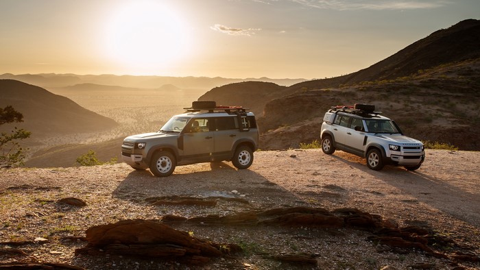 Two Land Rover Defenders in a desert at sunset