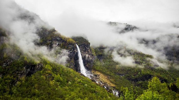 Waterfall cascading down a misty mountain covered in green trees