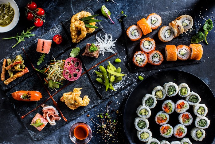 Sushi platter with various rolls, tempura, and prosciutto