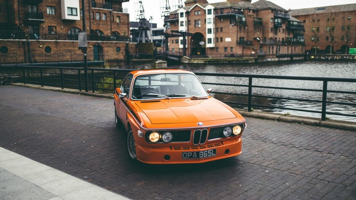 Orange BMW E9 sports car parked by a canal in England