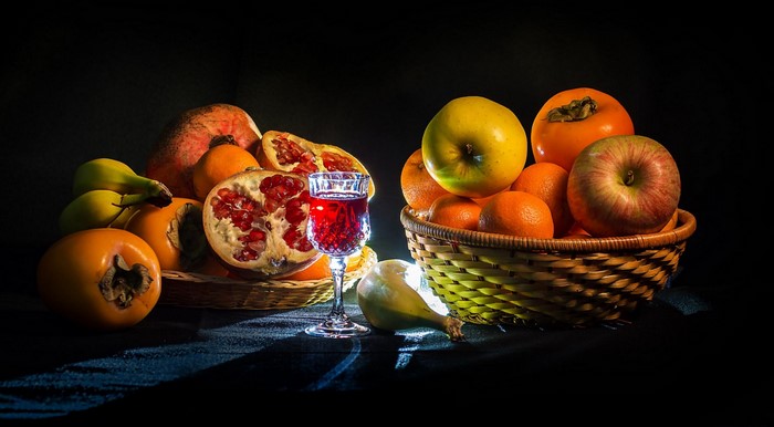 Still life with fruits, pomegranate, and glass of red liquid