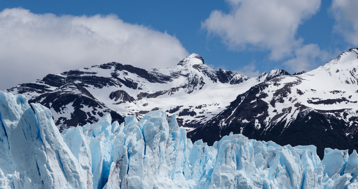Glacier and snow-capped mountains under a cloudy sky