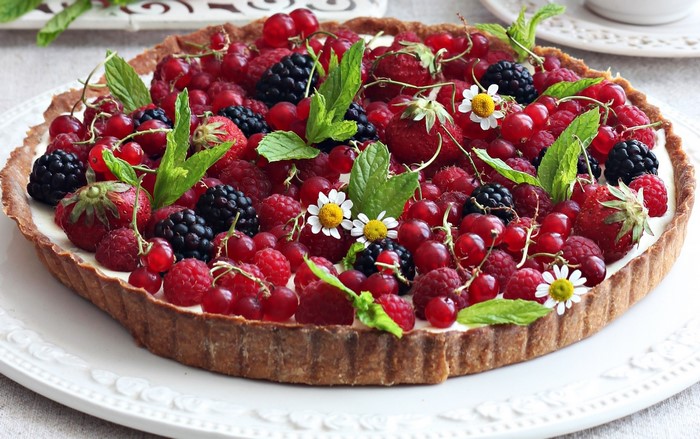 Berry tart with cream and mint leaves