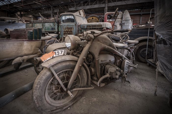 Old dusty motorcycle and trucks in a garage