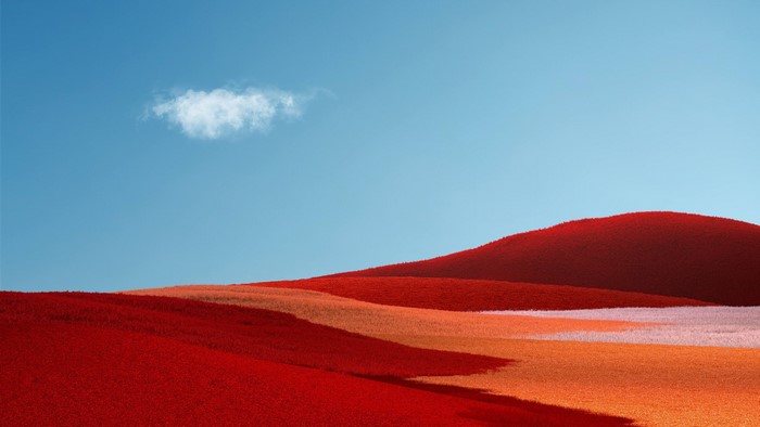 Red and orange hills under a blue sky with a cloud