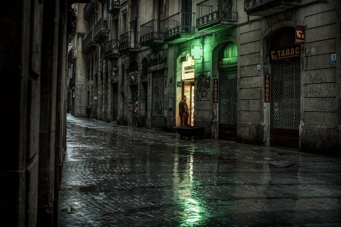 Man standing in a pharmacy on a wet street in Barcelona, Spain