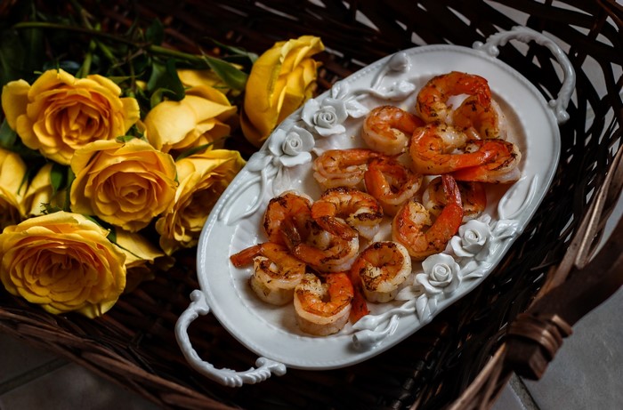 Grilled shrimp on a decorative plate with yellow roses