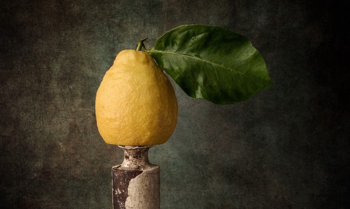 Still life of a lemon with a leaf on a pedestal