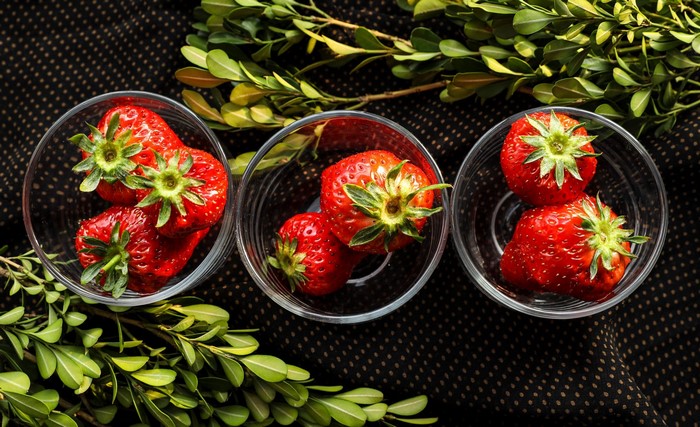 Strawberries in glass bowls with greenery