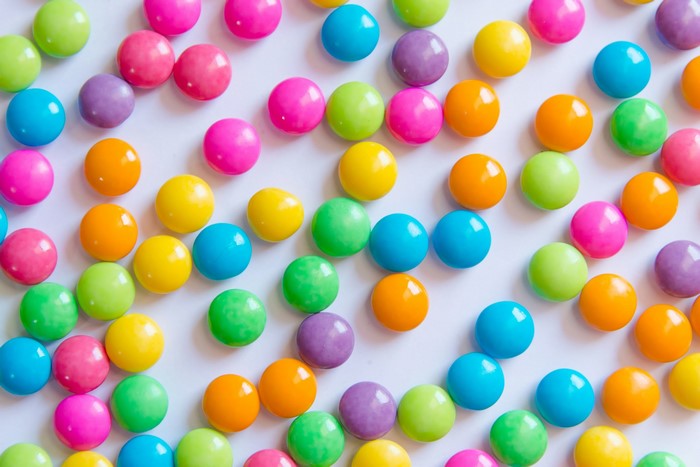 Colorful round sweets scattered on a white surface
