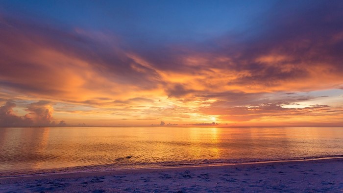 Sunset over the ocean with colorful clouds and beach