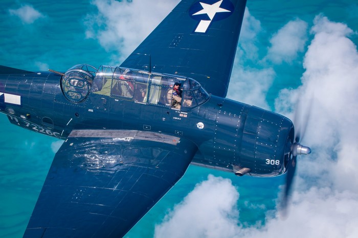 Blue Grumman TBF Avenger military aircraft flying over water