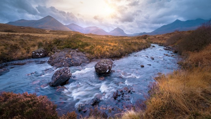 River flowing through Scottish mountains under sun rays