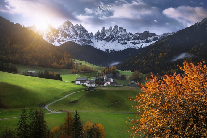 Idyllic valley village with snow-capped mountains at sunrise