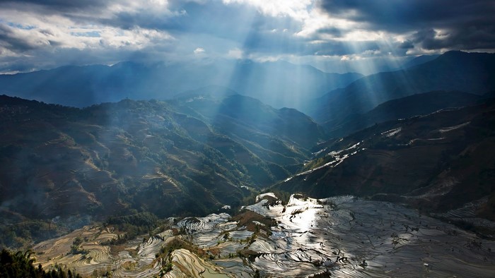 Sun rays over terraced rice fields in China