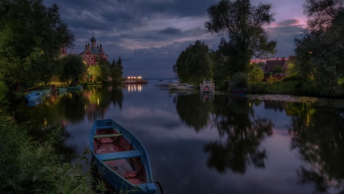 Boats on a river at dusk with a church and houses
