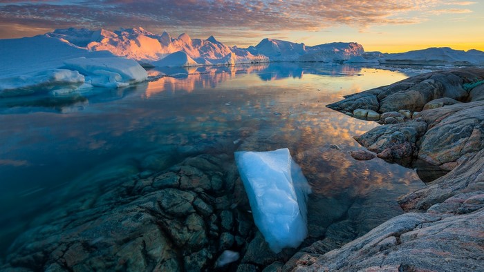 Sunset over Ilulissat Icefjord in Greenland with icebergs and rocks