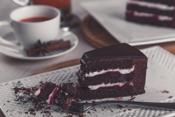 Chocolate cake with cream and cherry on a plate with a fork
