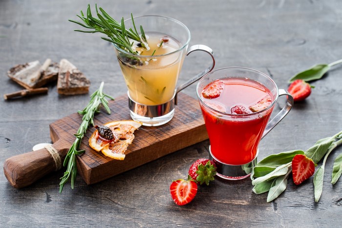 Two glasses of drinks with fruits and herbs
