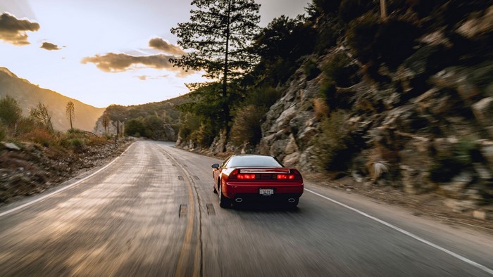 Red Acura NSX driving on a mountain road at sunset