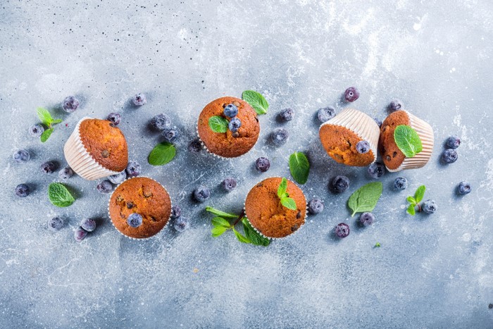Blueberry muffins with mint and blueberries on a gray surface