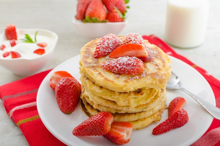 Stack of pancakes with strawberries and yogurt