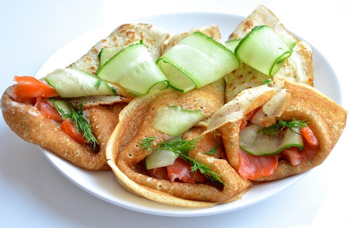 Pancakes with salmon, cucumber, and dill on a plate