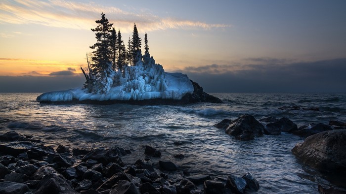 Frozen island with trees on a lake at sunrise