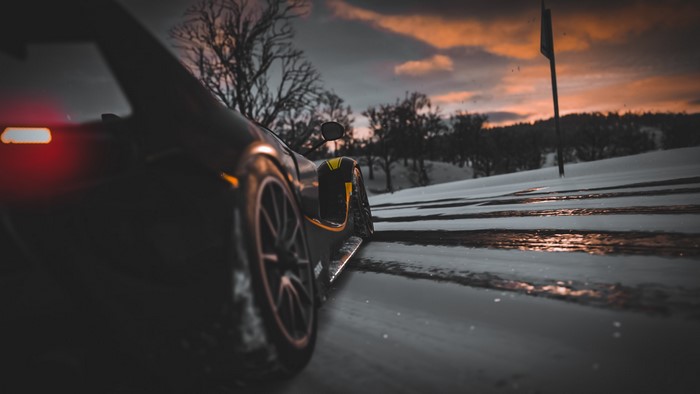 Ferrari FXX K driving on a snowy road at sunset