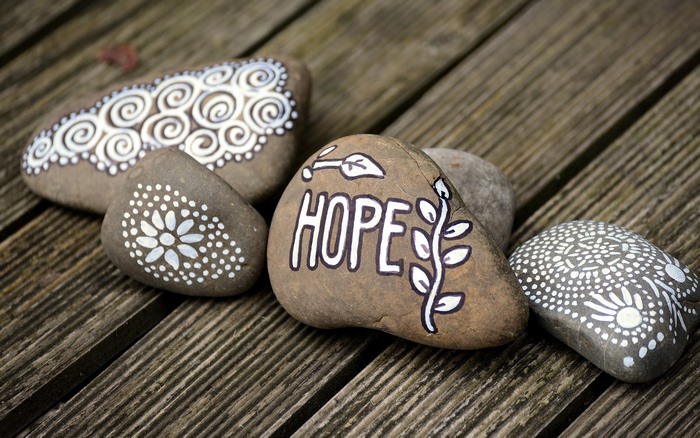 Painted stones with the word HOPE and decorative patterns