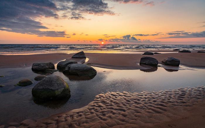 Sunset over the Baltic Sea in Latvia with rocks