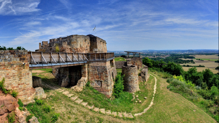 Ruins of a stone castle on a hill with a wooden bridge