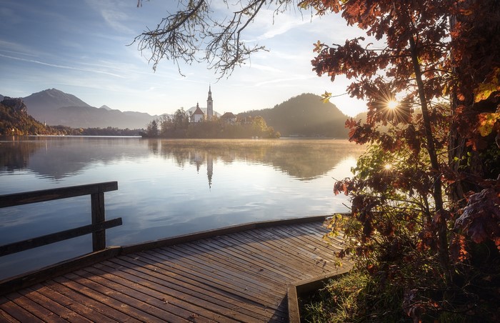 Lake with island church and mountains at sunrise