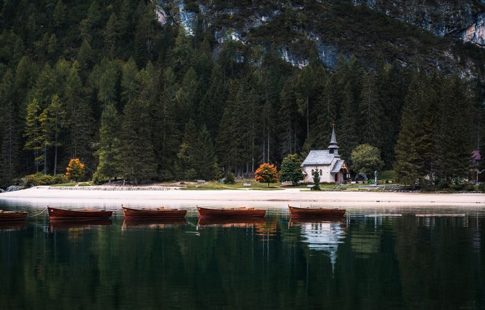 Boats on a lake in front of a church and forest