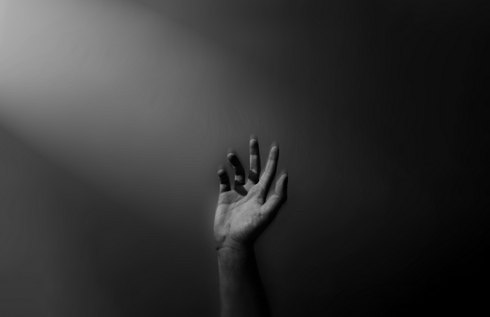 A hand reaching up from darkness