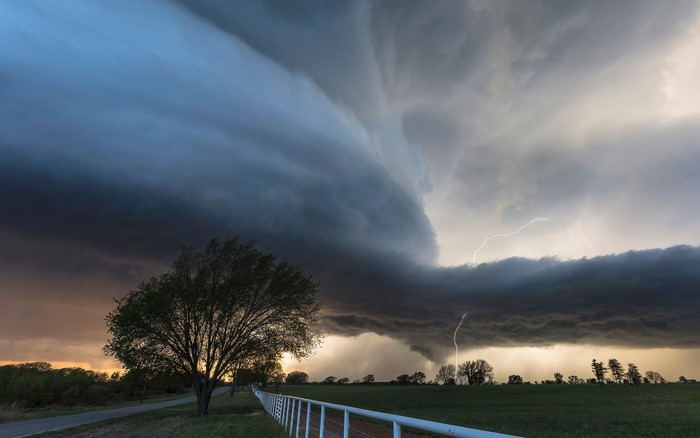 Storm clouds with lightning over a rural landscape with trees
