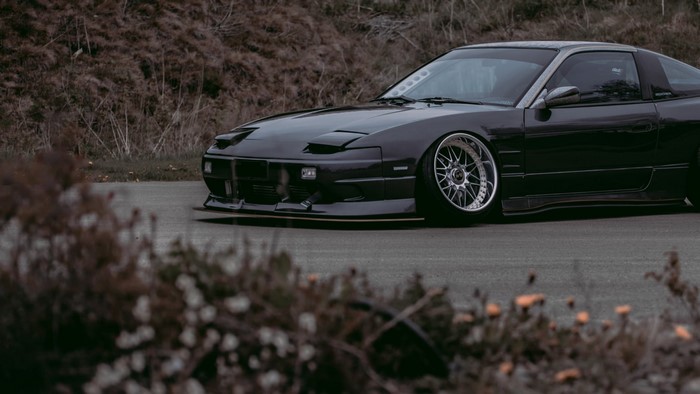 Dark Nissan 180SX with custom wheels and body kit