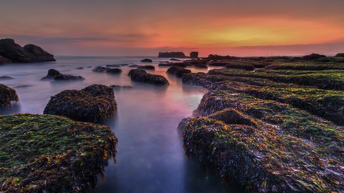 Long exposure sunset over mossy rocks in Bali, Indonesia