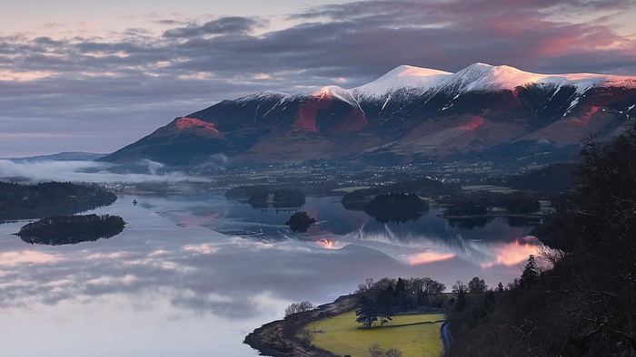 Snowy mountain peaks reflected in a lake at sunrise