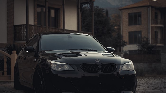 Black BMW E60 M5 parked in front of houses